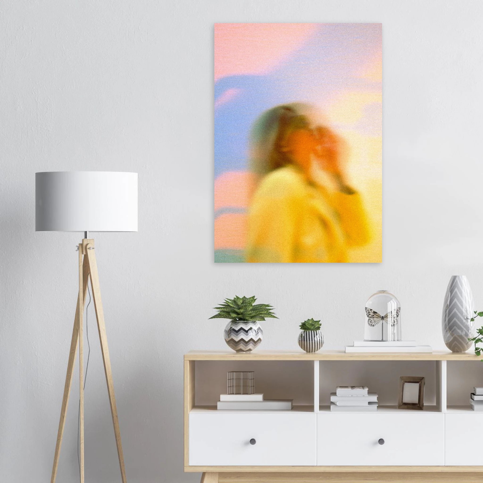 Abstract artwork poster of a woman in a yellow dress on a white wall above a piece of living room furniture.