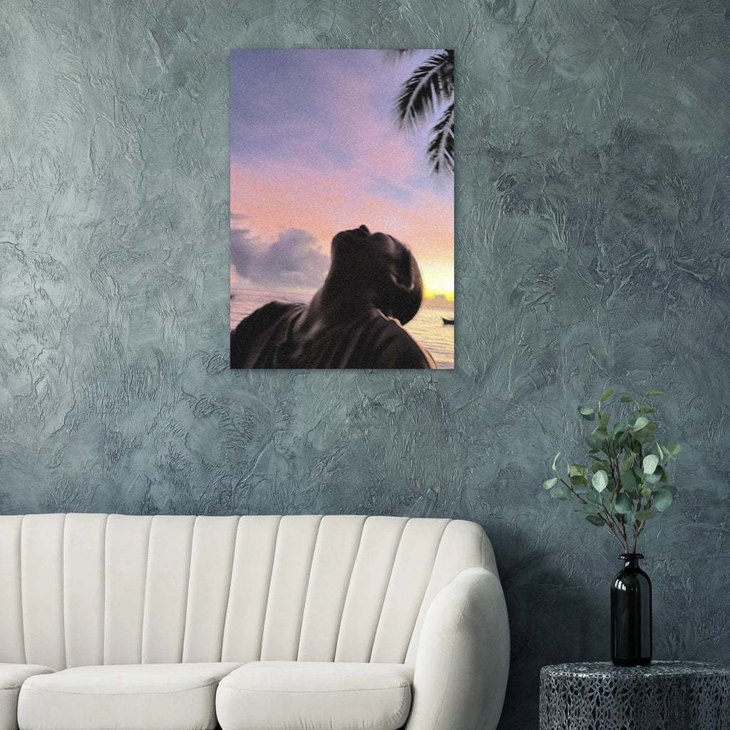 Artwork poster of a person looking at a sunset with palm trees on a wall above a couch.